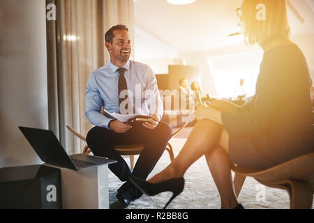 Deux jeunes gens d'affaires de rire en allant sur des notes et discuter de travailler ensemble dans un bureau moderne Banque D'Images