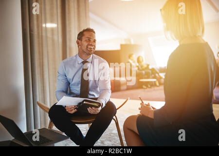 Deux jeunes gens rire ensemble en allant au travail et la discussion notes in a modern office Banque D'Images