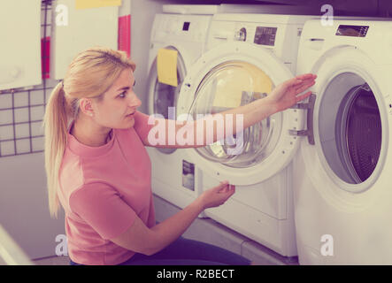 Femme au foyer positive choisit lave-linge en magasin d'appareils ménagers Banque D'Images