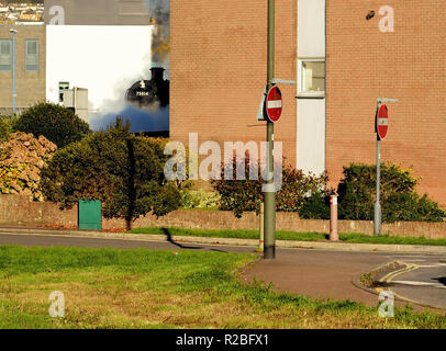 Train à vapeur dans un quartier résidentiel de Paignton au passage à niveau du chemin des sables bitumineux. Banque D'Images