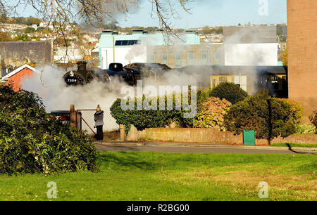 Train à vapeur dans un quartier résidentiel de Paignton au passage à niveau du chemin des sables bitumineux. Banque D'Images