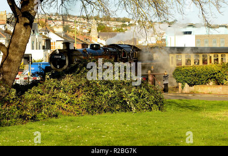 Train à vapeur dans un quartier résidentiel de Paignton au passage à niveau du chemin des sables bitumineux. Banque D'Images