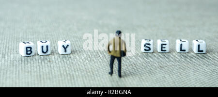 Libre de miniatures de businessman standing in front of white dices avec vendre et acheter des mots écrits sur eux Banque D'Images