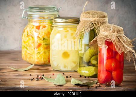 Ensemble de légumes fermentés dans des bocaux sur table rustique en bois. Salade de chou choucroute concombres tomates cerise et ananas en boîte. Concept Banque D'Images