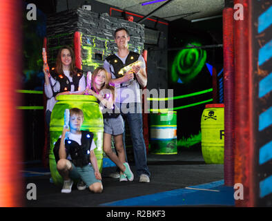 Portrait d'enfants heureux et parents avec leurs canons laser au cours de jeu lasertag in dark room Banque D'Images