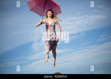 Young attractive young woman jumping in sky avec parapluie Banque D'Images