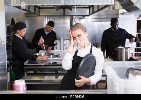 Portrait en colère jeune serveuse debout avec plateau de service vide en cuisine de restaurant Banque D'Images