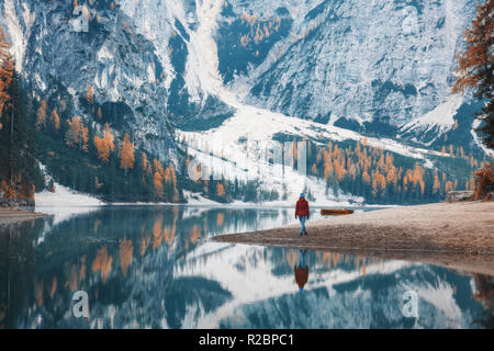 Femme debout sur la côte du lac Braies le matin en automne. Dolomites, Italie. Paysage avec fille, célèbre lac avec belle réflexion en w Banque D'Images