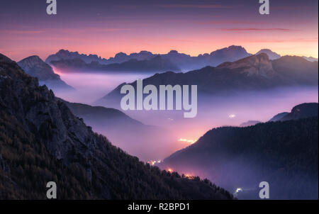 Montagnes en brouillard à belle nuit à l'automne en Dolomites, Italie. Paysage avec la montagne alpine valley, nuages bas, forêt, ciel mauve avec des étoiles, c Banque D'Images