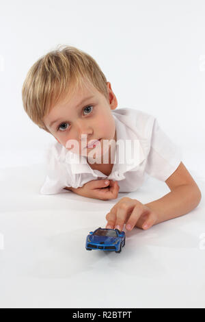 Cute blonde blue eyed petit Garçon jouant avec des jouets de voiture Banque D'Images