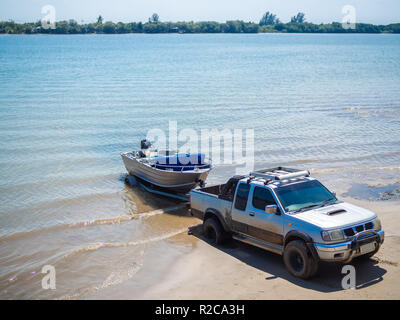 Bateau à moteur d'être tiré avec la camionnette remorque sur la plage. Banque D'Images