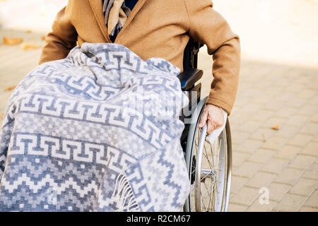 Hauts homme handicapé en fauteuil roulant avec plaid sur les jambes équitation par street Banque D'Images