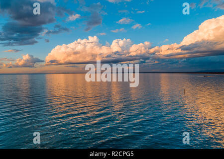 Côte de l'océan au coucher du soleil - nuages sur les eaux de la baie calme Banque D'Images