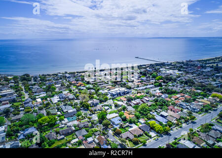 Vue aérienne du quartier résidentiel à proximité du littoral de l'océan et de longue jetée en bois avec des voiliers. Banque D'Images