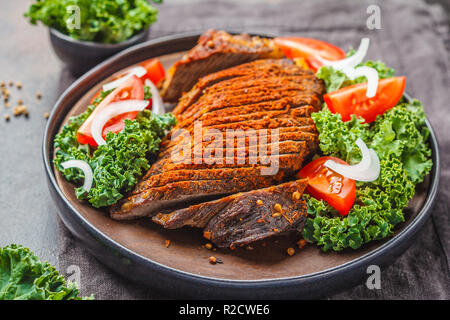 Au four avec du boeuf épicé salade de chou dans une plaque noire sur un fond sombre. Banque D'Images