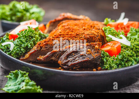 Au four avec du boeuf épicé salade de chou dans une plaque noire sur un fond sombre. Banque D'Images