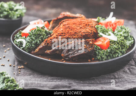 Au four avec du boeuf épicé salade de chou dans une plaque noire sur un fond sombre. Banque D'Images