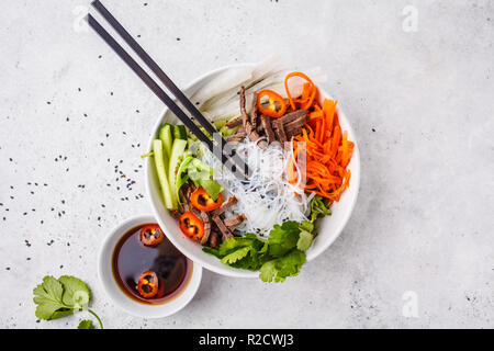 Bun cha bol à salade. Nouilles de riz vietnamienne au boeuf et légumes en salade chili bol blanc, vue du dessus. Banque D'Images