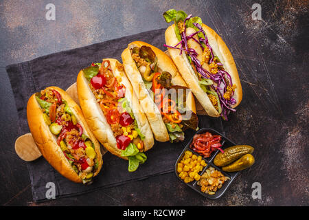 Hot-dogs avec garnitures variées sur un fond sombre, vue d'en haut. Concept alimentaire traditionnel américain. Banque D'Images