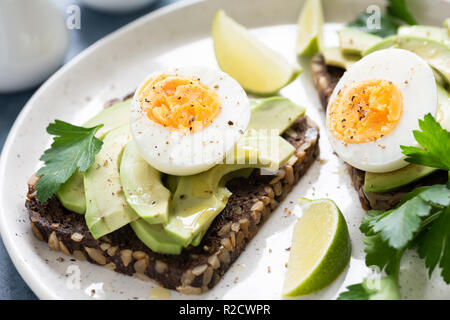 Toast de seigle à grains entiers avec de l'avocat et l'oeuf garni de persil. Collation santé, le petit déjeuner et déjeuner Banque D'Images