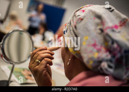 Mainz, Allemagne. 19 Oct, 2018. Une femme avec le cancer utilise un bâton de masquage dans son maquillage classe. Le traitement du cancer par chimiothérapie ou radiothérapie traitement peut changer radicalement l'apparence de la peau avec la perte de cheveux, perte de cils et sourcils ou des irritations de la peau. Le fichier de donneurs de moelle osseuse, Allemand (DKMS) propose pour les femmes concernées en particulier sur il a coordonné les cours de mise à niveau. (Pour 'dpa avec make-up pinceau et la peinture contre les traces de cancer' à partir de 19.11.2018) Crédit : Andreas Arnold/dpa/Alamy Live News Banque D'Images