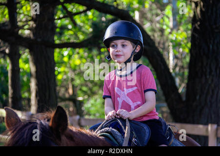 Foi close up of young woman, 8 ans - 10, s'amuser, unplugged, montant un cheval à l'extérieur avec la lumière du soleil filtrant à travers les arbres dans les enclos Banque D'Images