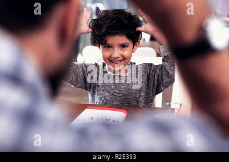 Cute smiling Dark-eyed boy wearing chandail gris joué des tours Banque D'Images