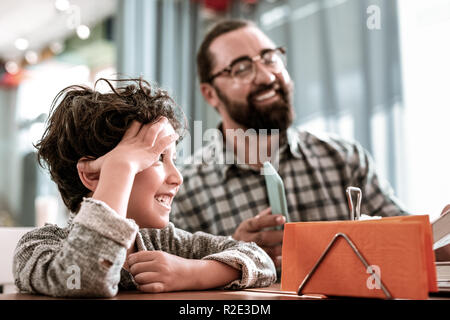 Transmission d'heureux père et papa assis dans une cafétéria en attente de commande Banque D'Images