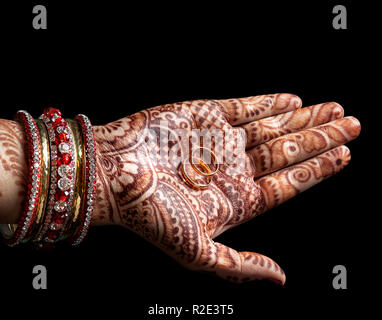 Les anneaux de mariage en femme palm avec peinture au henné sur fond noir Banque D'Images