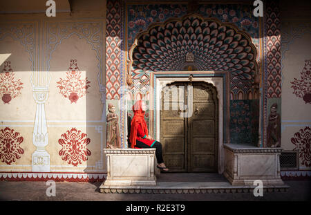 Femme au foulard rouge assis près de la porte de Lotus dans City Palace de Jaipur, Rajasthan, Inde Banque D'Images