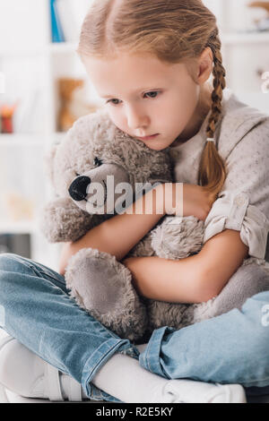 Close-up portrait of enfoncée petit enfant embrassant son ours en peluche Banque D'Images