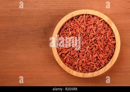 Une photo d'un riz rouge à grain long, tourné par le haut dans un bol en bois sombre sur un fond rustique with copy space Banque D'Images