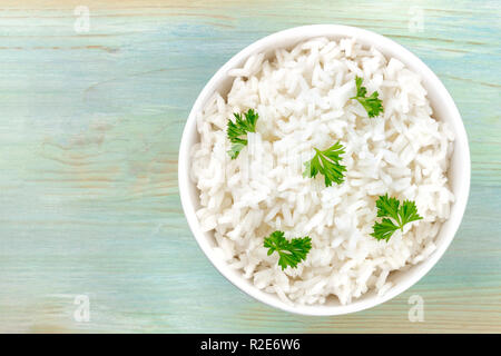 Une photo prise à la verticale d'un bol de riz blanc long grains cuits, tourné à partir de ci-dessus, sur un fond bleu sarcelle avec une place pour le texte Banque D'Images