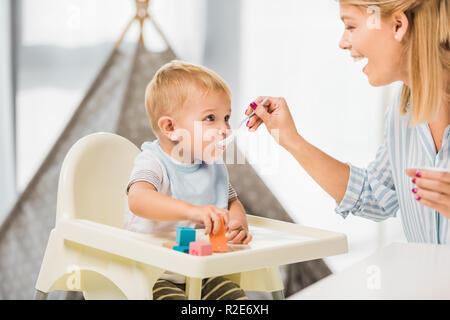 Maman heureuse dans son alimentation avec des aliments pour bébé Chaise haute Banque D'Images