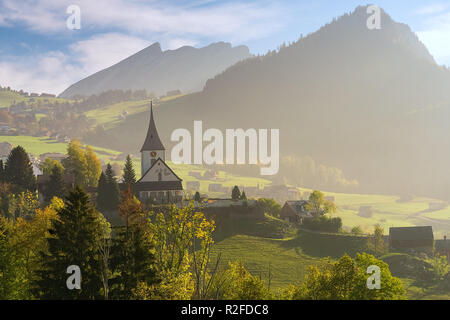 Paysages de montagne alpine avec église dans un petit pays, entre prairies et des montagnes , sur belle journée ensoleillée. Banque D'Images