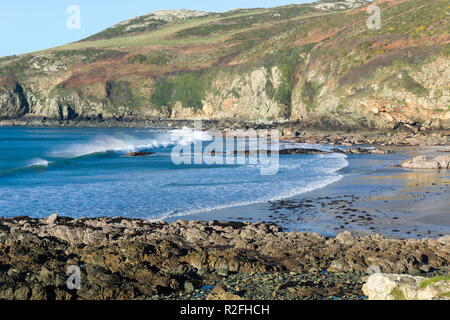 Baie de l'église à la belle île gallois d'Anglesey. Falaises rocheuses et vagues se brisant sur la plage. Un jour ensoleillé, froid, hiverne. Banque D'Images