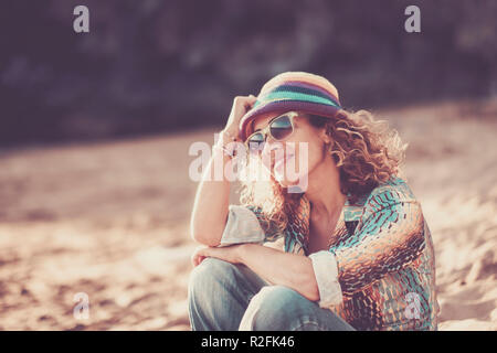 Happy smiling caucasian woman moyen-âge assis à la plage et profiter de l'été. sourire et vous détendre après le travail. Locations et voyage concept avec les personnes âgées et attrayant avec style coloré Banque D'Images