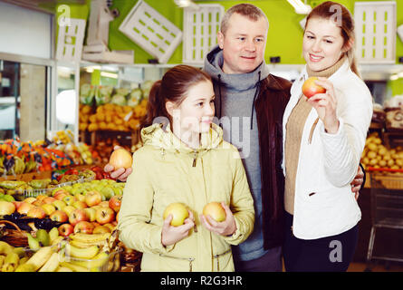 Belle Famille avec preteen fille à la recherche de pommes fraîches en magasin de fruits Banque D'Images