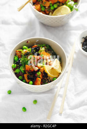 Deux végétariens poke bol. Le tofu, le riz, les algues, les pois verts et oignons savoureux et sain la nourriture végétarienne Banque D'Images