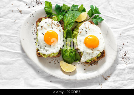 Vue de dessus les toasts avocat sain pour le petit déjeuner ou le déjeuner avec le pain de seigle, pain grillé et purée d'avocat d'œufs au plat sur fond blanc Banque D'Images