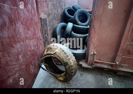 Vieille voiture obsolètes de pneus de camions et voitures stockées dans des contenants en métal à l'usine de recyclage des déchets après le tri pour traitement ultérieur. Banque D'Images