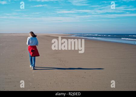 Femme marchant le long de la plage à l'automne, Juist, Frise orientale, Basse-Saxe, Allemagne Banque D'Images