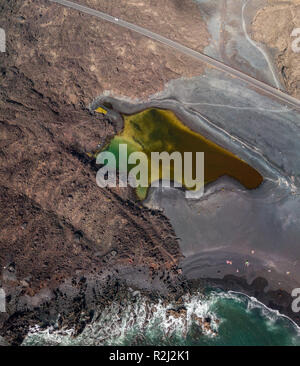 Vue aérienne du petit lac sous la montagne Bermeja, vue de la plage noire et la route côtière. Lanzarote, îles Canaries, Espagne Banque D'Images