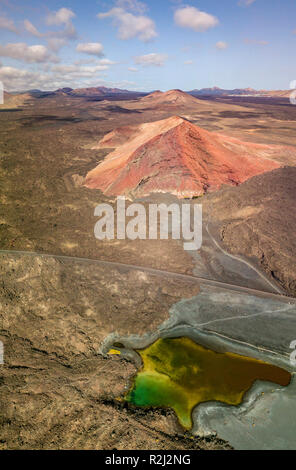 Vue aérienne de la montagne Bermeja, entouré de champs de lave. La route côtière qui traverse les champs de lave noire et un petit lac. Lanzarote, Espagne Banque D'Images