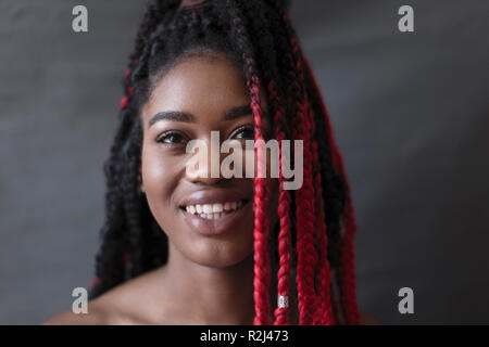 Portrait souriant, confiant jeune femme avec des tresses rouges Banque D'Images