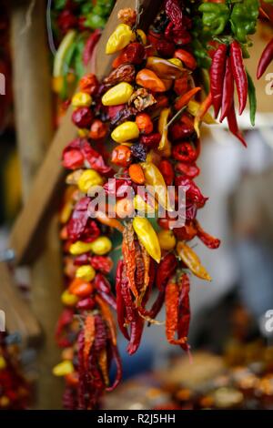 String de piments séchés multicolores séchant au soleil sur un marché méditerranéen Banque D'Images