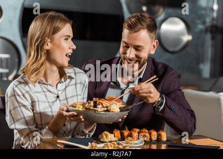 Beautfiful surpris femme tenant la plaque avec de délicieux fruits de mer tout en couple having dinner in restaurant Banque D'Images