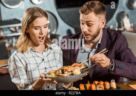 Surpris femme tenant la plaque avec les fruits de mer tout en couple having dinner in restaurant Banque D'Images