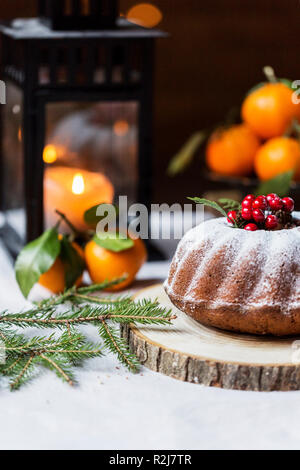 Noël et Nouvel an avec des baies gâteau et l'arbre de Noël brunch sur du papier craft à wood board, lanterne derrière et des mandarines à fond blanc Banque D'Images