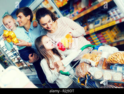 Heureux parents de deux filles d'acheter le yogourt aux fruits et au lait Banque D'Images